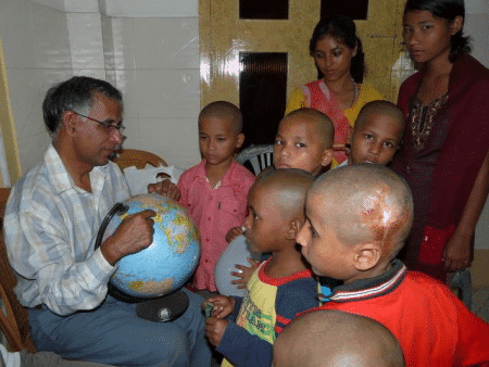 Bishal, vorne rechts im Jahr 2009. Der Gründer und ehemalige Heimleiter Fr. Lukose zeigt den Kindern wo der Besuch aus Deutschland herkommt. Die Haare der Kinder? Kurzer Prozess nach einem Läusebefall…